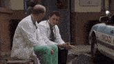 two doctors are sitting on a bench in front of a police car .