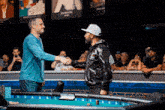 two men shaking hands in front of a crowd with one wearing a jacket with gs on it