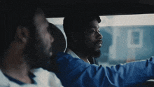 two men are sitting in a car and one is driving