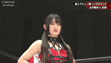 a woman in a red dress stands in a ring with a stardom logo on the bottom
