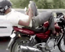 a man is sitting on the back of a motorcycle .