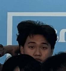 a man is sitting in a crowd of people looking at the camera .