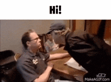 a man in a wheelchair is talking to another man in a hat .