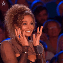 a woman with curly hair is smiling in front of a microphone with a star in the corner
