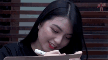 a girl is writing on a clipboard with a marker and smiling ..
