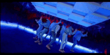a group of young men are dancing in a room with blue lights .
