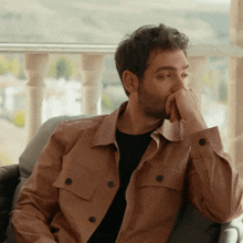 a man sitting in a chair with his hand to his face