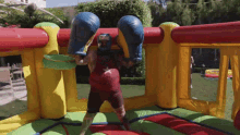 a man wearing boxing gloves and a helmet stands in an inflatable boxing ring