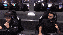 a man wearing headphones sits next to another man wearing headphones in front of a pro am sign
