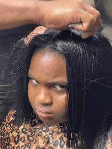 a little girl with a leopard print shirt has her hair brushed