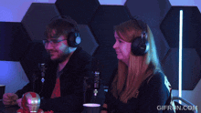 a man and a woman wearing headphones are sitting in front of a microphone and the website gifrun.com is visible