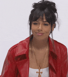 a woman wearing a red jacket and a gold necklace with a cross on it