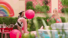 two women are playing with balloons in a backyard with a netflix logo in the corner .
