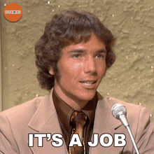 a man in a suit and tie speaking into a microphone with the words it 's a job below him