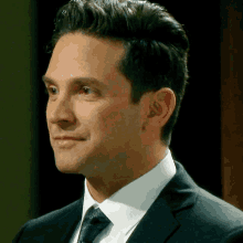 a man in a suit and tie is smiling and looking away from the camera