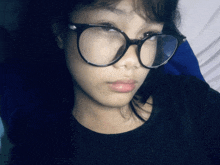 a young woman wearing glasses and a black shirt