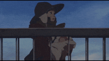 a woman in a hat holds a baby behind a fence