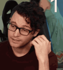 a man wearing glasses and a red shirt has the number 1 on the bottom