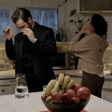 a man in a suit is standing next to a woman in a kitchen