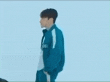 a man in a squid game uniform is standing in front of a blue background .