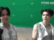 two young men are standing in front of a green screen that says team epis