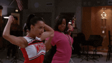 two cheerleaders wearing warriors uniforms are dancing together in a room