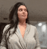 a woman is wearing a gray robe and looking up at the sky .