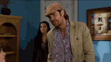 a man wearing a hat is standing in front of a woman