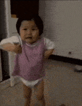 the baby is wearing a diaper and a purple shirt and is running .