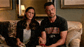 a man and woman are sitting on a couch and the man is wearing a georgia shirt