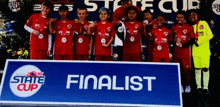 a group of young boys are posing for a picture in front of a state cup finalist sign
