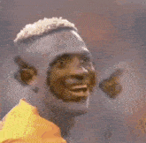 a soccer player wearing a yellow jersey is smiling while holding a butterfly in his mouth .