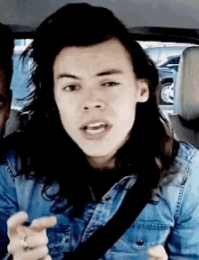 a man with long hair is wearing a denim shirt and a black belt