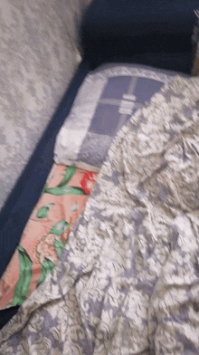 a bed with a floral comforter and a plaid pillow