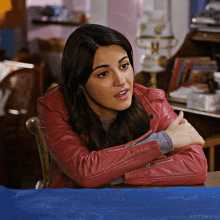 a woman in a red leather jacket sits at a table with a blueprint on it that says editsmaite