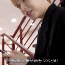 a man in a black jacket is writing on a piece of paper while standing on a set of stairs