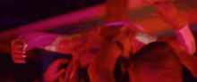 a group of people are dancing in a dark room with purple lights .