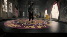 a man in a hoodie is standing in a room with a circular rug