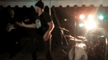 a man stands in front of a drum set with a drummer behind him
