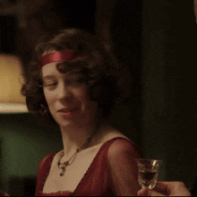 a woman in a red dress smiles while holding a shot glass