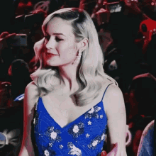 a woman in a blue dress stands in a crowd