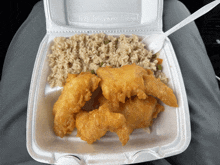 a styrofoam container with fried chicken rice and vegetables