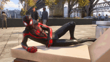 a man in a spiderman suit is laying on a chair