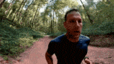 a man in a blue shirt is running through a forest