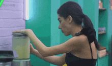 a woman is using a blender to make a drink .