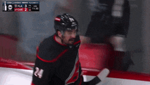 a hockey player with the number 24 on his jersey stands on the ice