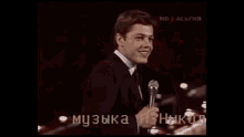 a man in a suit and tie is singing into a microphone on a stage .