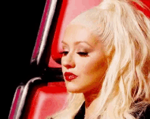 a close up of a woman 's face with blonde hair and red lips .