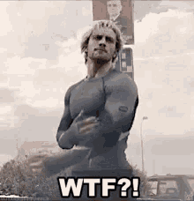 a man in a superhero costume is standing in front of a sign that says wtf ? .
