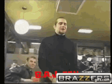 a man in a black turtleneck stands in front of a brazzers sign ..